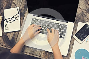 Female hands on laptop keyboard with another computer tablet on