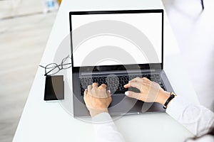 Female hands on laptop keyboard which stands on table.