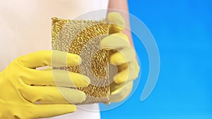 Female hands in latex gloves hold a sponge-scraper for washing Teflon surfaces