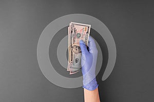 Female hands in latex rubber glove holds out money, several banknotes 50 US dollars