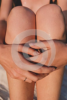 Female hands and legs in evening sun after swimming in the river.