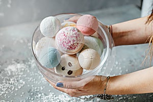 Female hands on a light background hold a bowl full of multi-colored balls for a bath, handmade