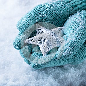 Una donna mani la luce lavorato maglia guanti intrecciate bianco stella sul bianco la neve. un 