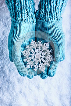 Una donna mani la luce lavorato maglia guanti scintillante favoloso Fiocco di neve sul bianco la neve. 