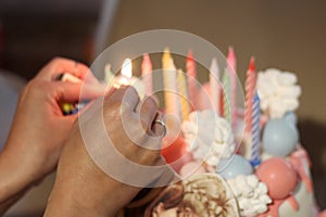 Female hands lighting candles on a birthday cake. The warmth and joy of a birthday celebration