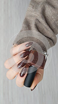 Female hands with long nails with brown nail polish