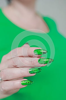 Female hands with long nails and green and black thermo manicure