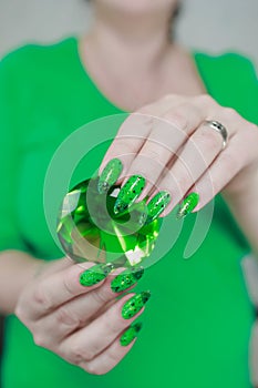 Female hands with long nails and green and black thermo manicure