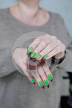 Female hands with long nails and green and brown manicure