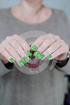 Female hands with long nails and green and brown manicure