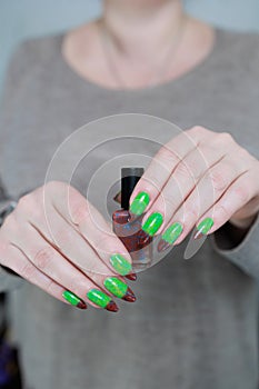 Female hands with long nails and green and brown manicure