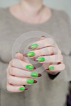 Female hands with long nails and green and brown thermo manicure