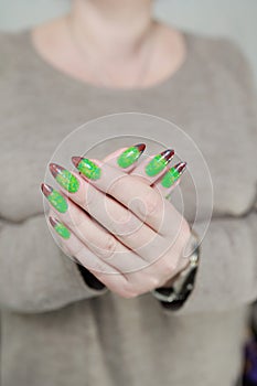 Female hands with long nails and green and brown thermo manicure