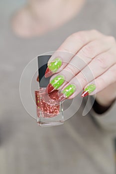 Female hands with long nails and green and brown thermo manicure