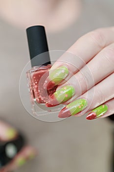 Female hands with long nails and green and brown thermo manicure