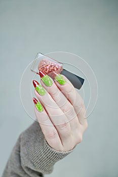 Female hands with long nails and green and brown thermo manicure