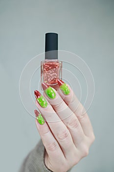 Female hands with long nails and green and brown thermo manicure