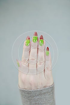 Female hands with long nails and green and brown thermo manicure