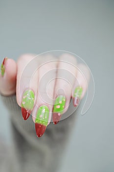 Female hands with long nails and green and brown thermo manicure