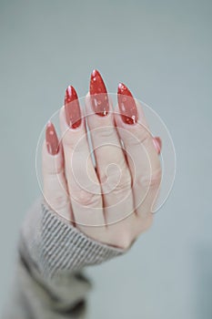 Female hands with long nails and green and brown thermo manicure