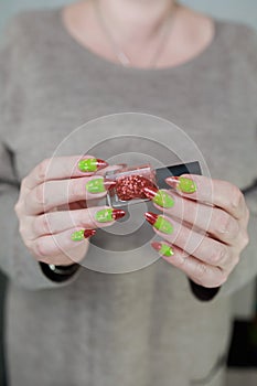 Female hands with long nails and green and brown thermo manicure