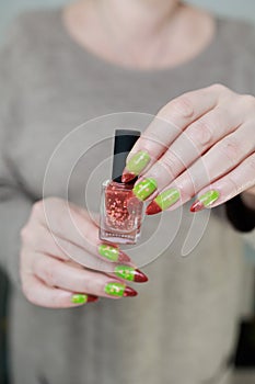 Female hands with long nails and green and brown thermo manicure