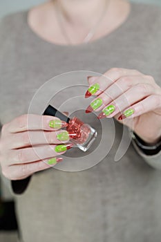 Female hands with long nails and green and brown thermo manicure