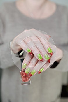 Female hands with long nails and green and brown thermo manicure