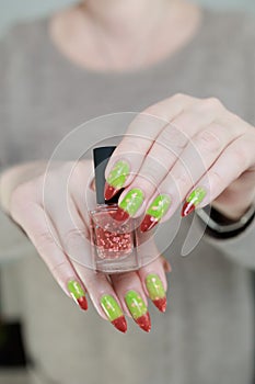 Female hands with long nails and green and brown thermo manicure