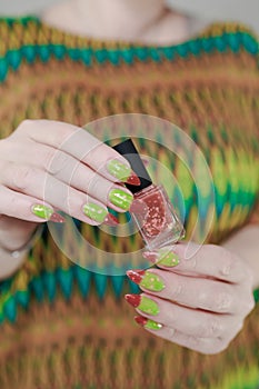 Female hands with long nails and green and brown thermo manicure