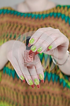 Female hands with long nails and green and brown thermo manicure