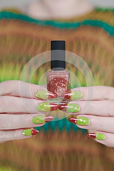 Female hands with long nails and green and brown thermo manicure