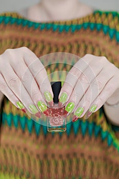 Female hands with long nails and green and brown thermo manicure