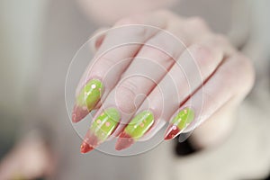 Female hands with long nails and green and brown thermo manicure