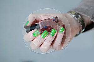 Female hands with long nails and green and brown manicure