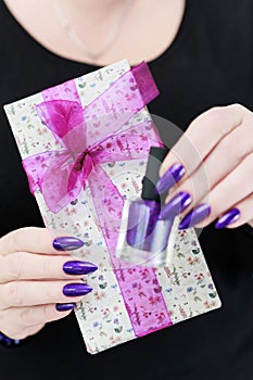 Female hands with long nails hold a gift box