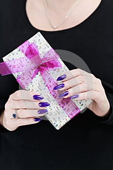 Female hands with long nails hold a gift box