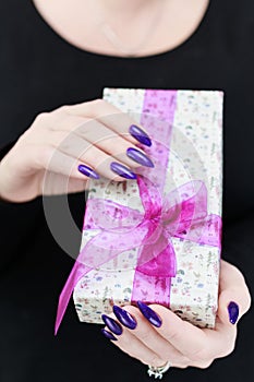 Female hands with long nails hold a gift box