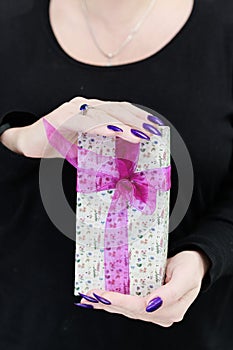 Female hands with long nails hold a gift box