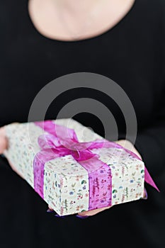 Female hands with long nails hold a gift box