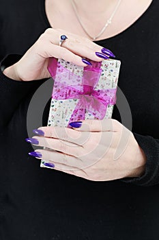 Female hands with long nails hold a gift box