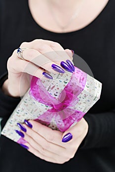 Female hands with long nails hold a gift box