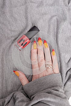 Female hands with long nails with yellow and red nail polish