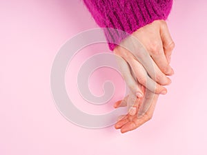 Female hands in magenta sweater on pink