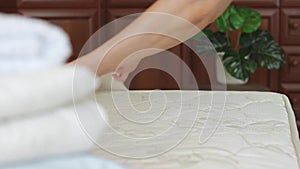 Female hands make bed linen at home or chambermaid hands set up white bed sheet in hotel room