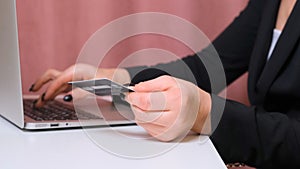 Female hands make a purchase on the Internet using a laptop, payment by card, close-up.