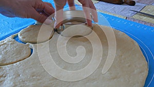 Female hands make shapes for future donuts with a special round ring on a special silicone mat for kneading the dough