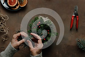 Female hands makes Christmas flower arrangement.