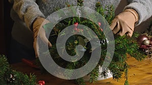 Female hands making Christmas flower arrangement using Christmas tree twigs