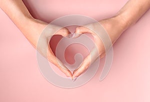 Female hands making heart on pink background. Love, friendship, peace concept. Valentine day, Birthday, Mothers Day.